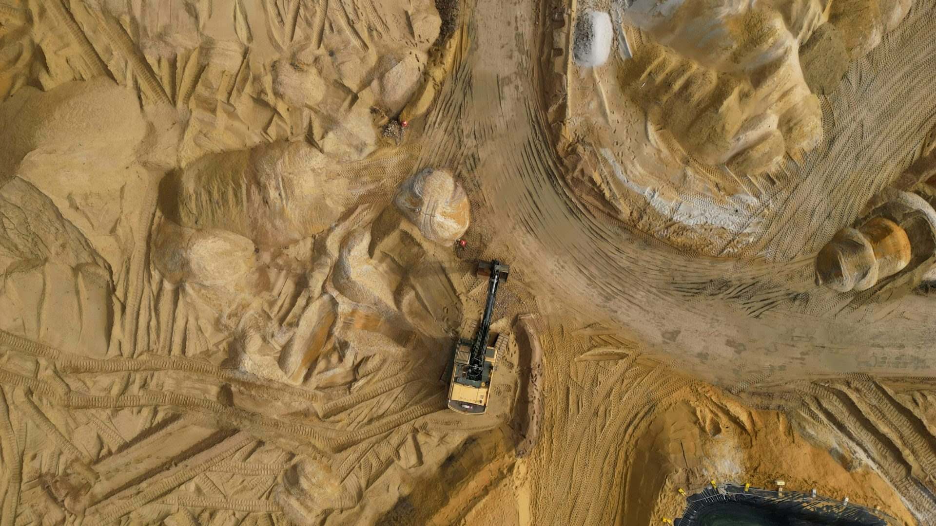 Ein Bagger arbeitet in sandigem Gelände.